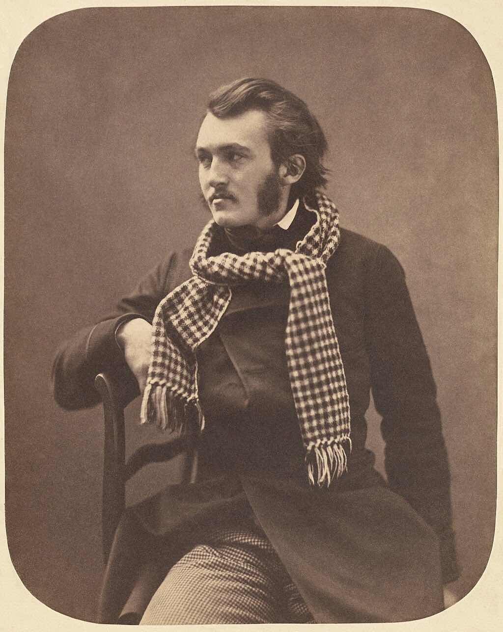 Vintage photograph on a salted paper print of Gustave Doré sitting on a chair and looking to his right.