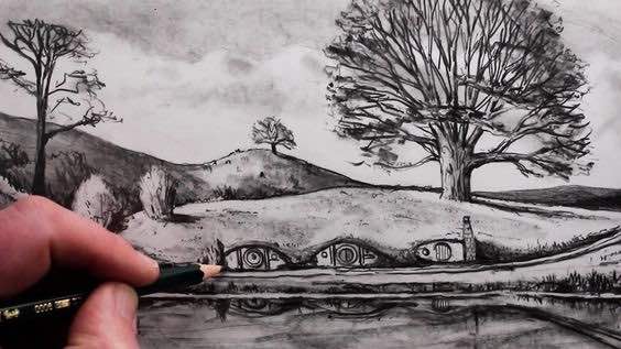 Artist sketching hobbit-like homes nestled in a scenic landscape with a large tree and peaceful surroundings.